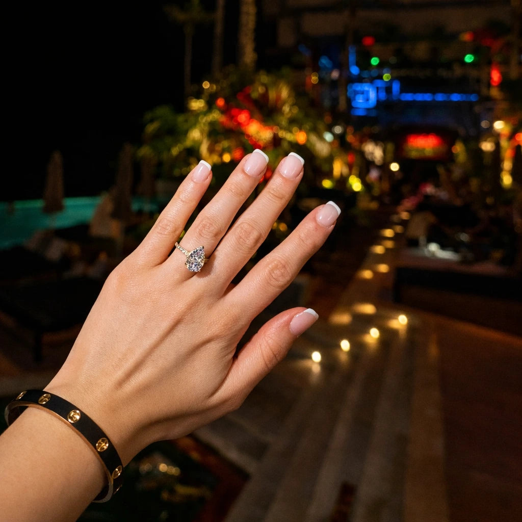 Hand wearing a gold cubic zirconia ring with a blurred night-time background