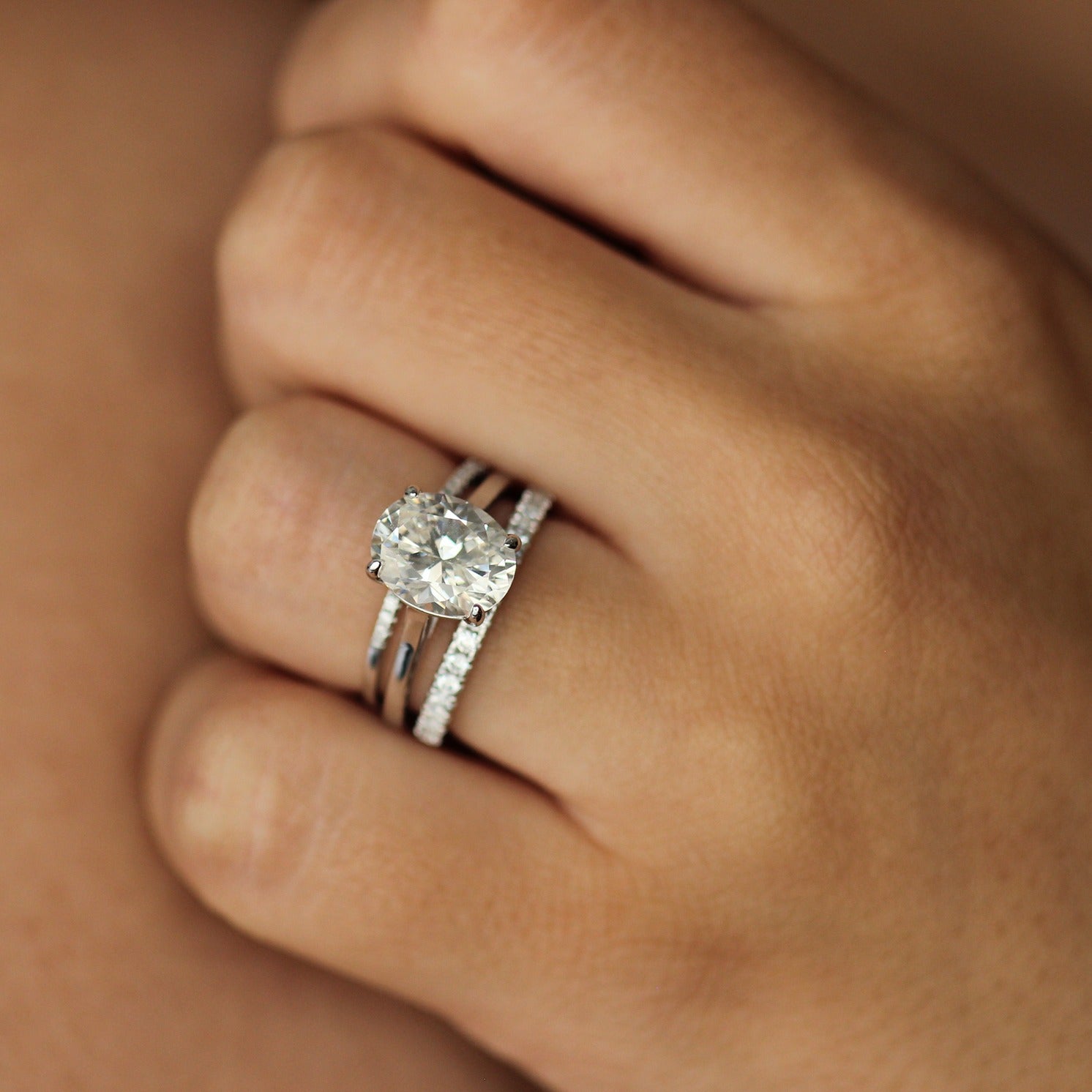 Silver cubic zirconia oval ring on hand with stacker pave rings