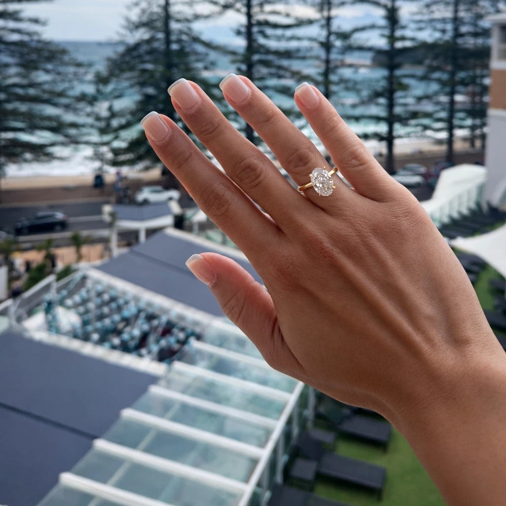 Hand wearing a 3.5ct oval ring with a blurred outdoor background