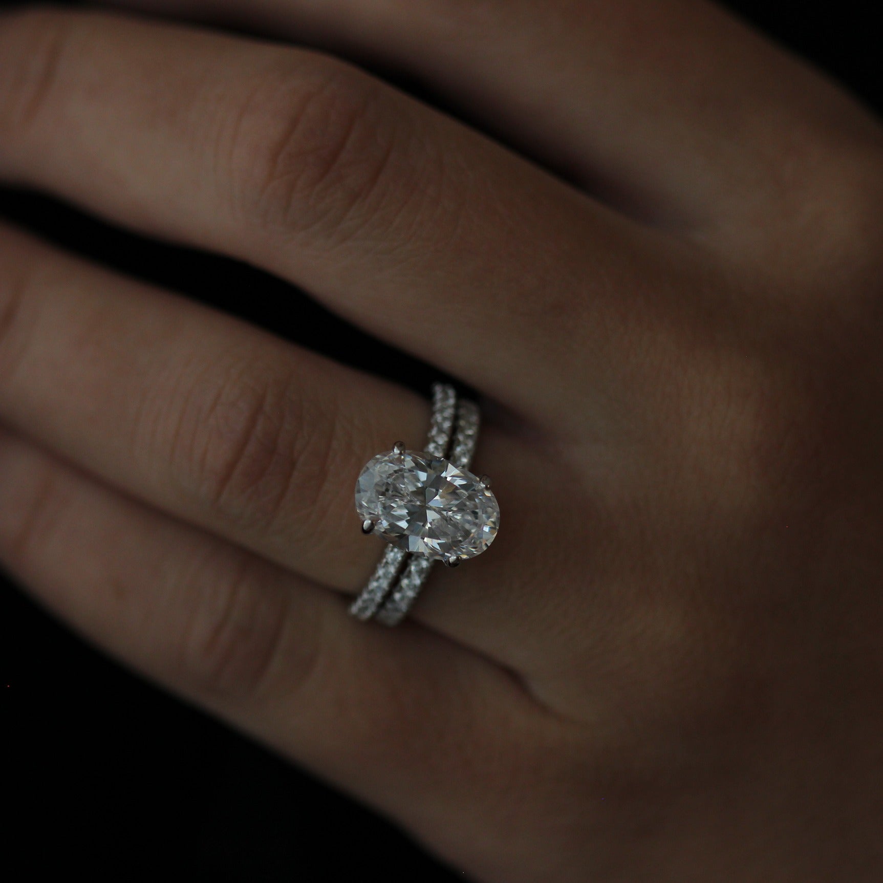 3.5ct oval ring on a finger with a dark background