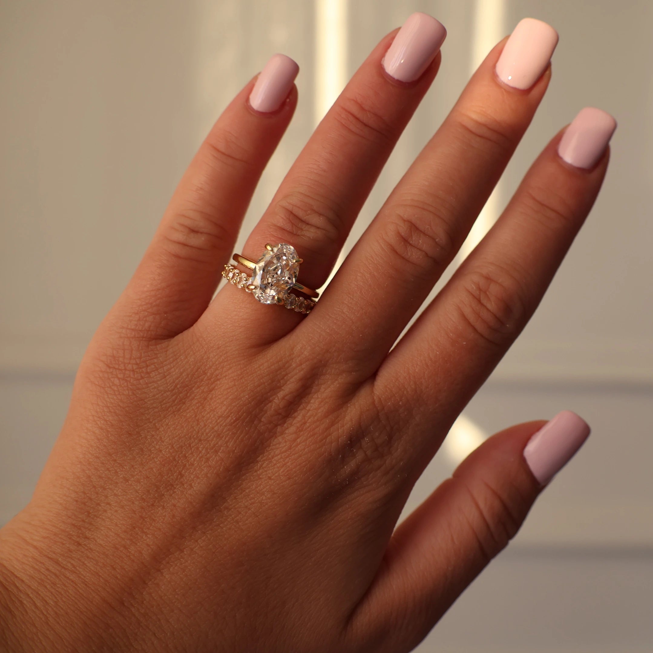 3mm gold oval eternity ring stacked with an oval solitaire engagement ring