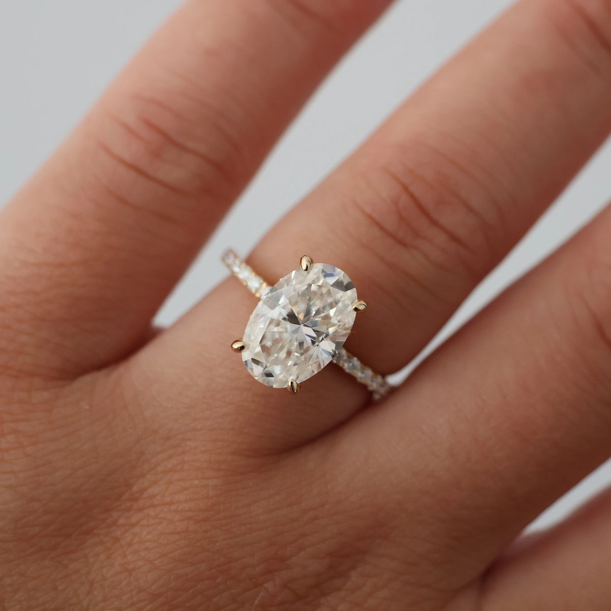 4 carat oval moissanite engagement ring with a pavé band in 14k gold fill