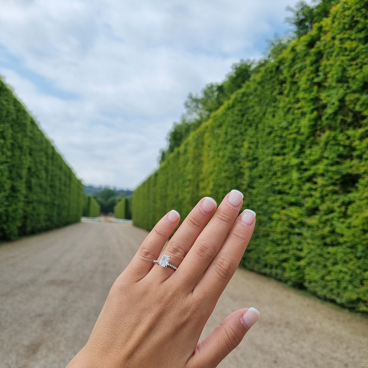 2 carat Radiant cut ring on hand in Gardens of Versailles