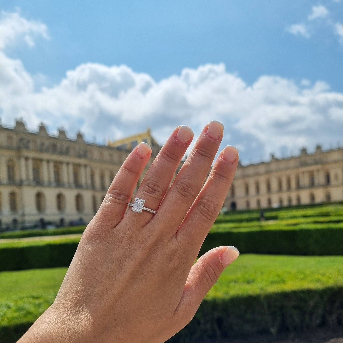 Radiant cut ring on hand in Palace of Versailles