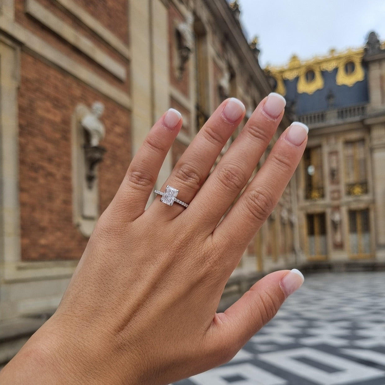 Radiant cut ring on hand in Palace of Versailles