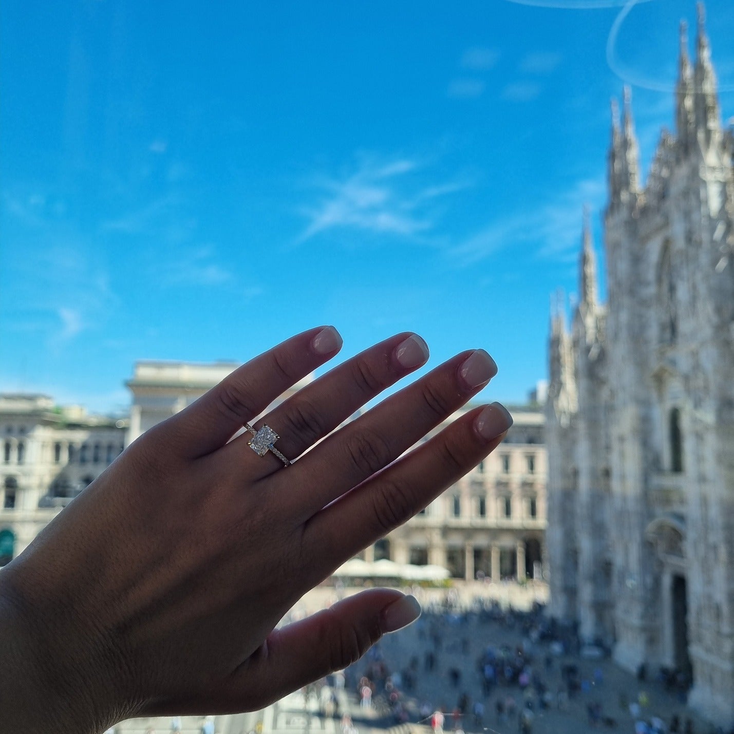 Gold radiant cut rectangle ring on hand in front of Duomo, Milan
