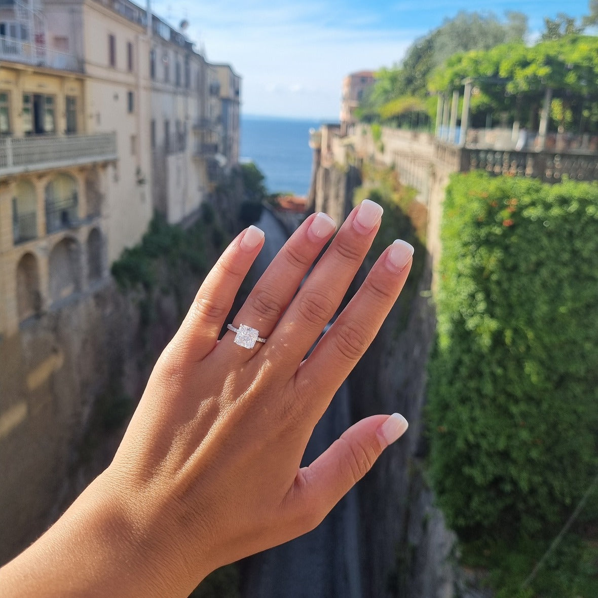 Silver radiant cut ring on hand in front of bridge Piazza Tasso, Sorrento