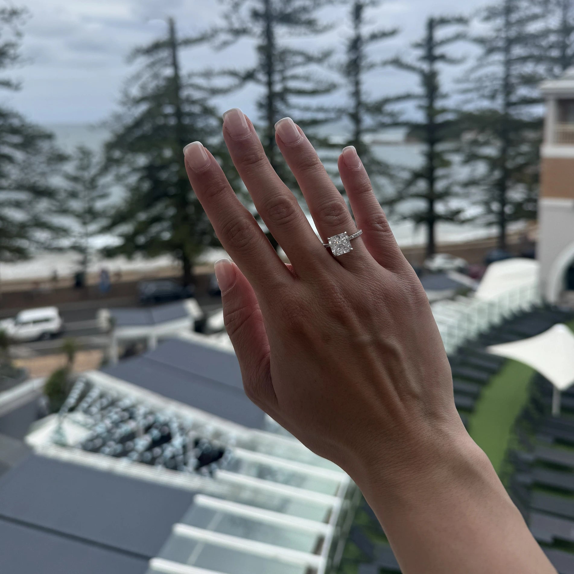 Hand wearing a square crushed ice ring with a blurred outdoor background