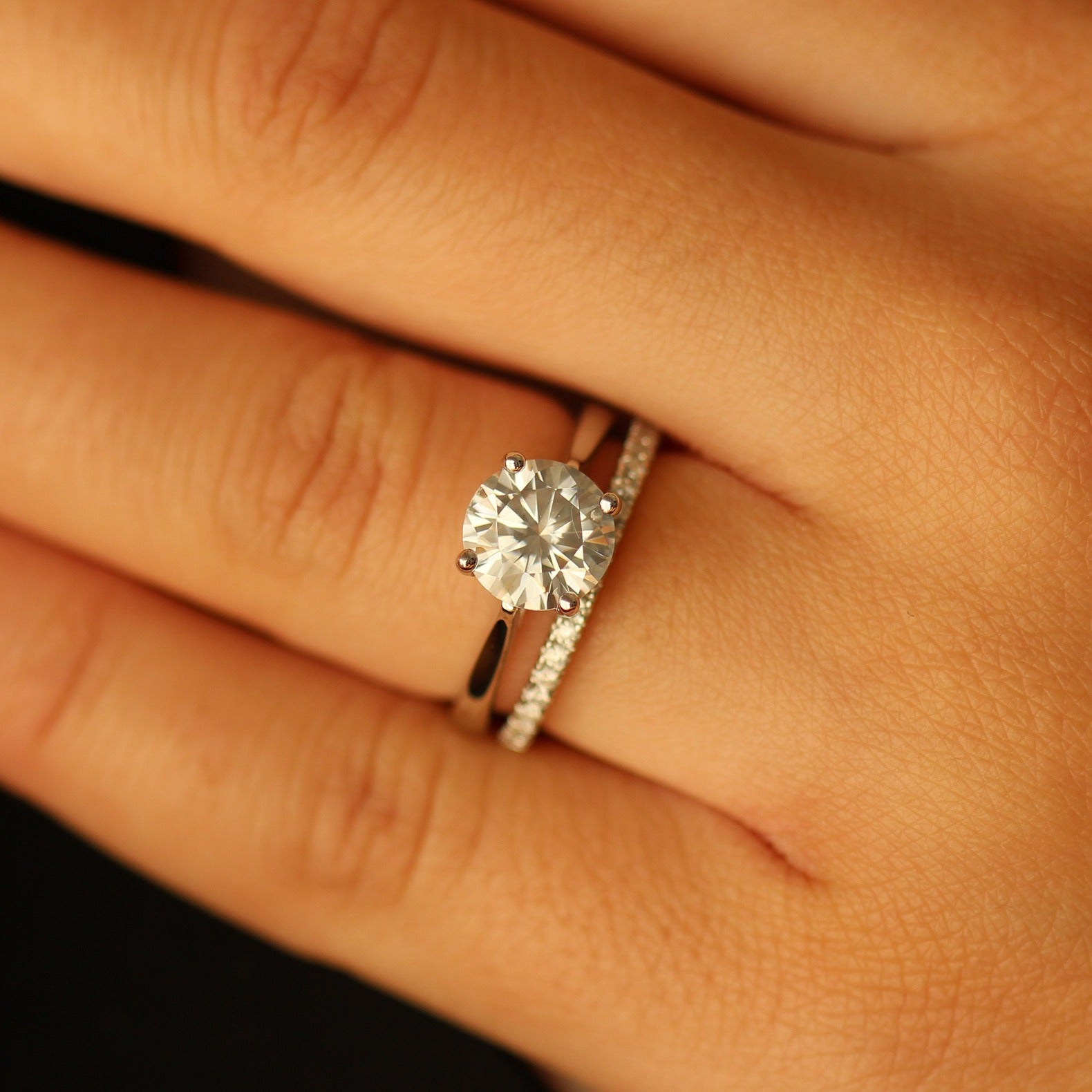 2ct round moissanite ring on hand with pave band