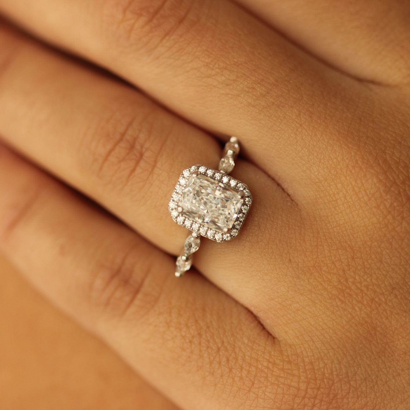 radiant cut halo ring with marquise stones on silver band on hand