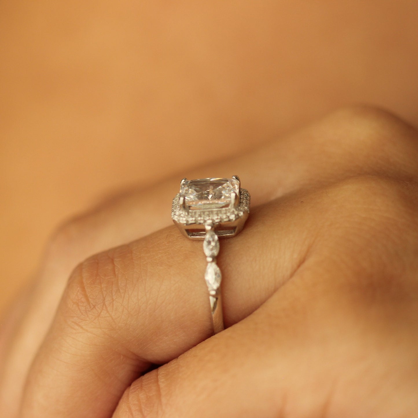 radiant cut halo ring with marquise stones on silver band on hand side profile