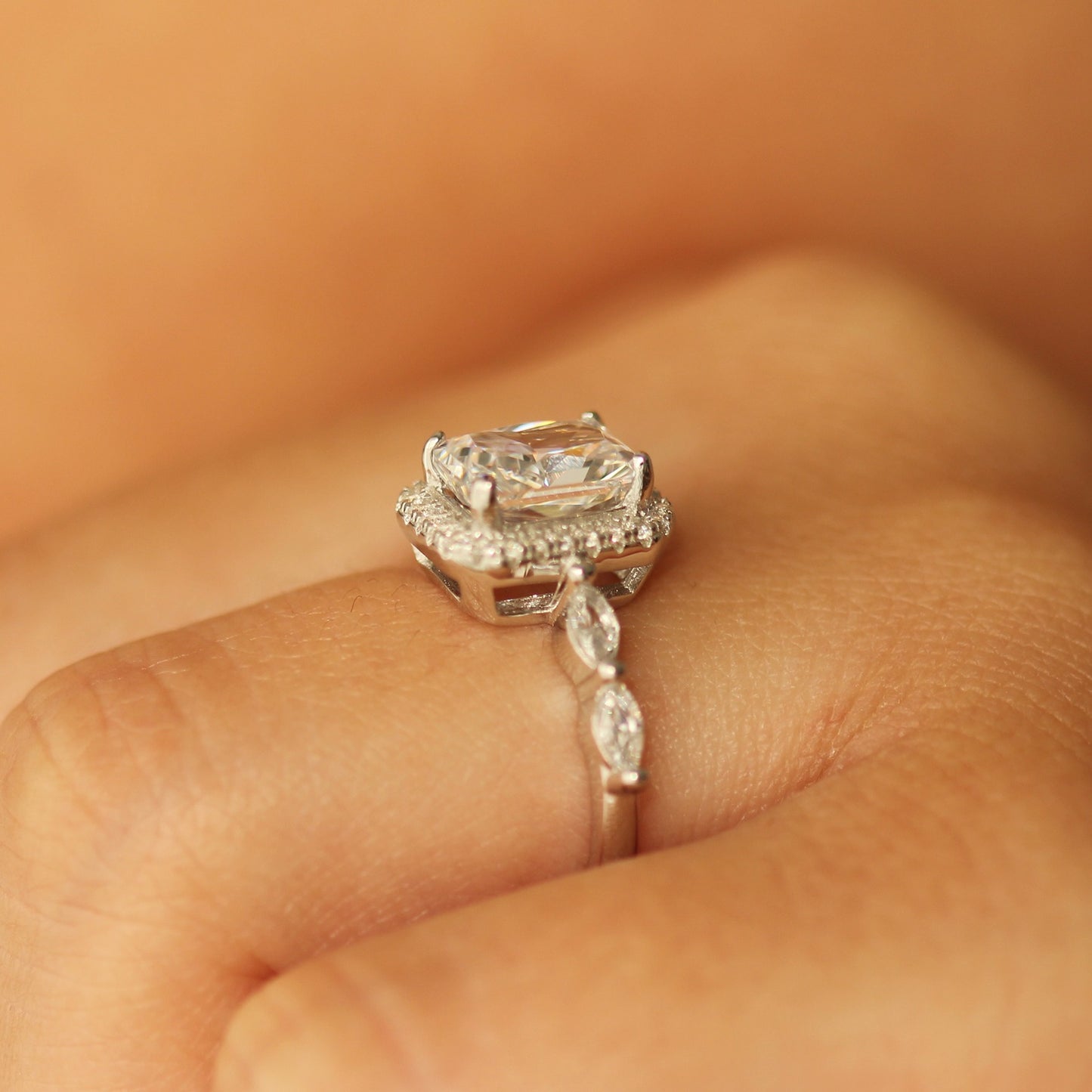radiant cut halo ring with marquise stones on silver band on hand side profile