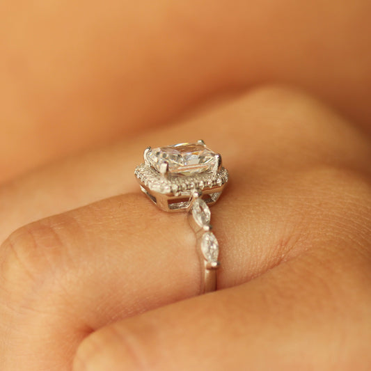 radiant cut halo ring with marquise stones on silver band on hand side profile
