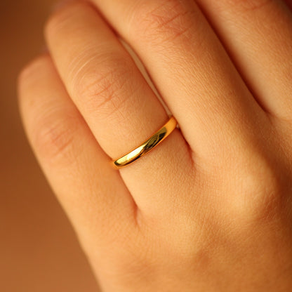 18k Gold vermeil ring on a person's finger with a warm brown background