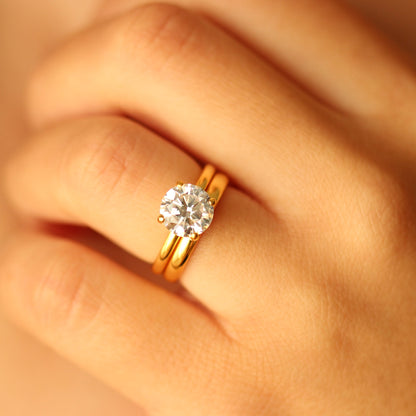 round cubic zirconia gold ring on hand with plain wedding band