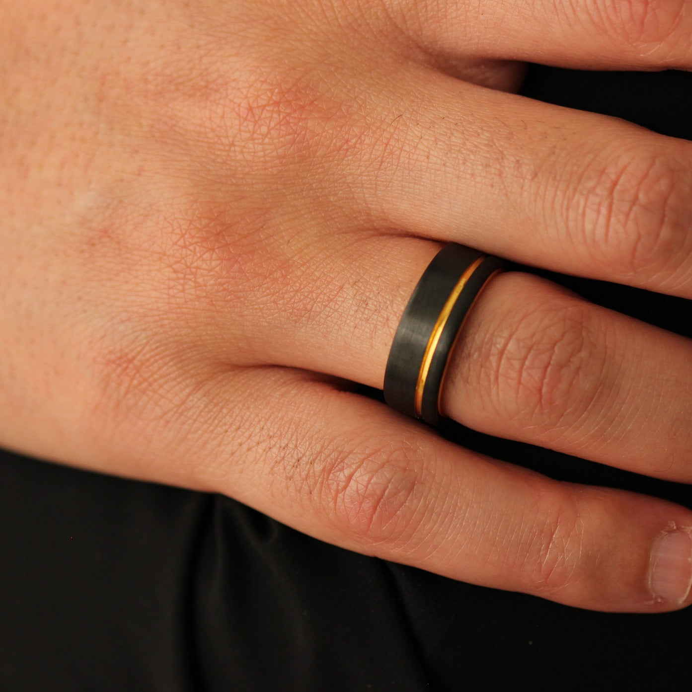 Men’s black wedding ring with a gold offset line accent