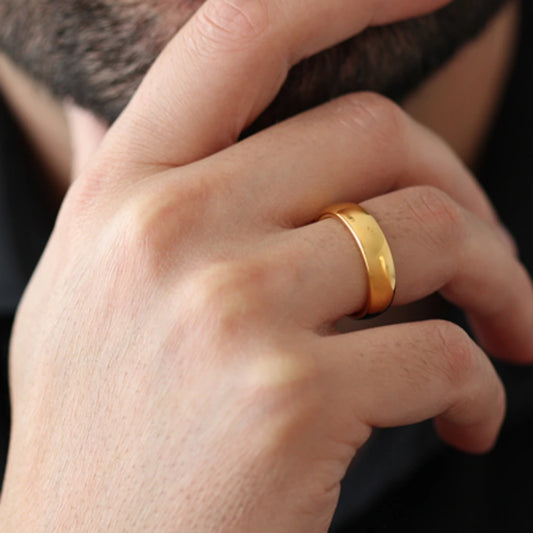 Close up of a men's hand wearing a polished gold tungsten ring