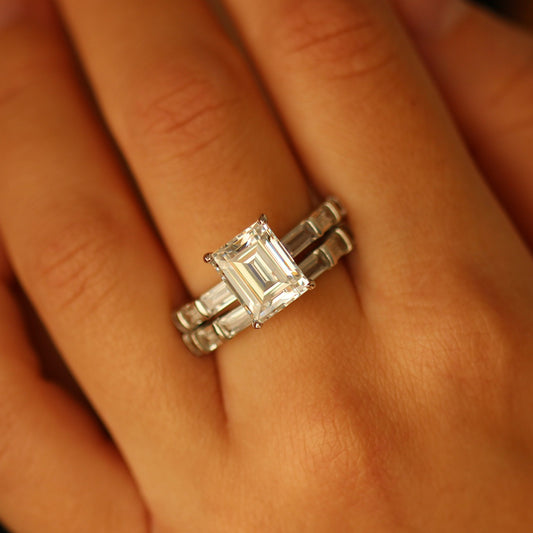 Silver ring with baguette diamonds and emerald cut ring on a person's finger