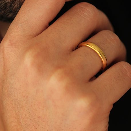 Man holding hand up to chin wearing polished gold wedding band