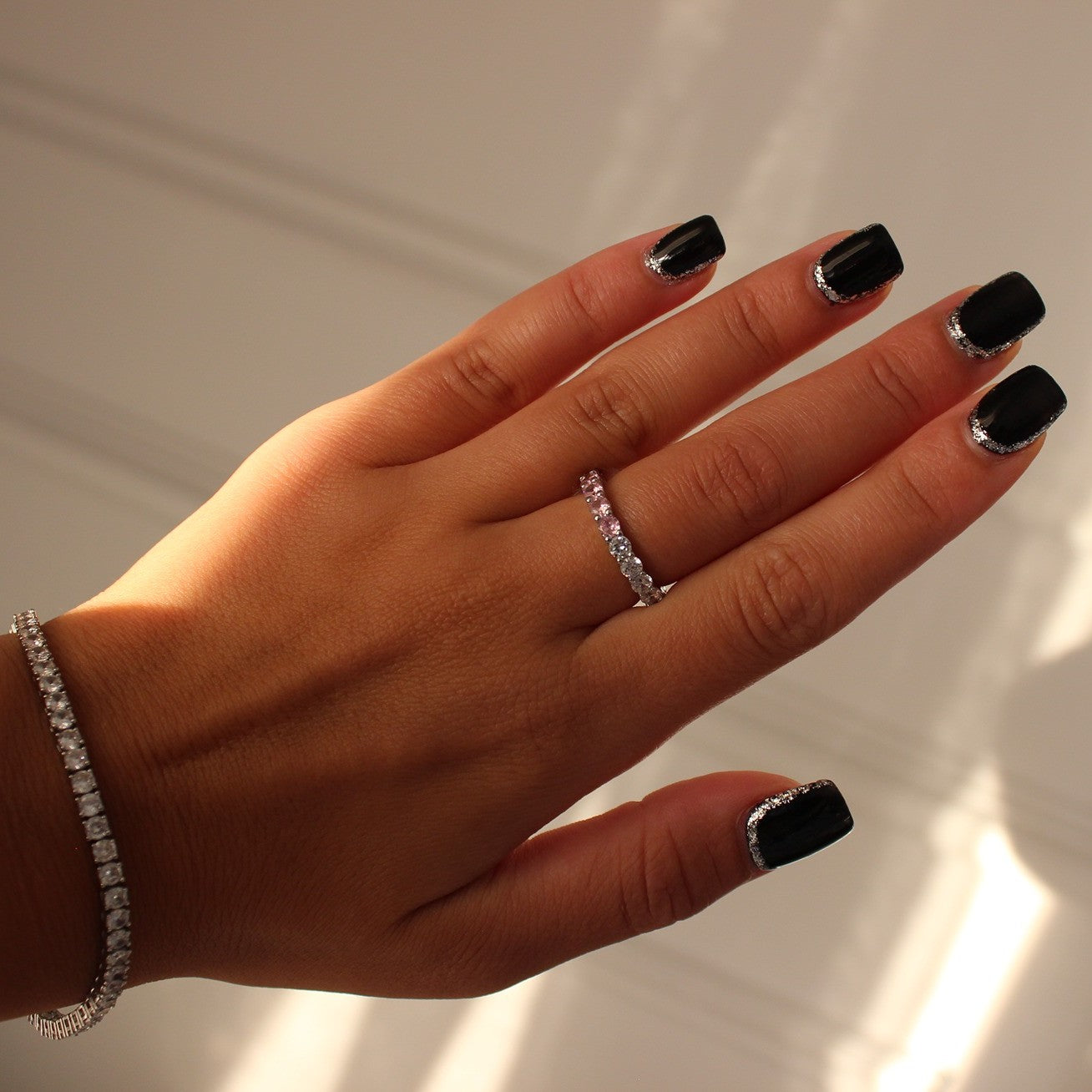 Pink eternity ring in silver on hand with silver tennis bracelet