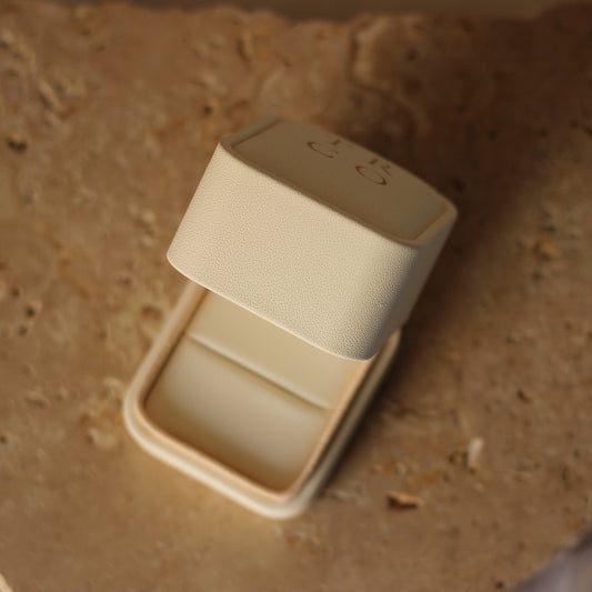 Travel Ring Co ivory proposal ring box in front of stone background