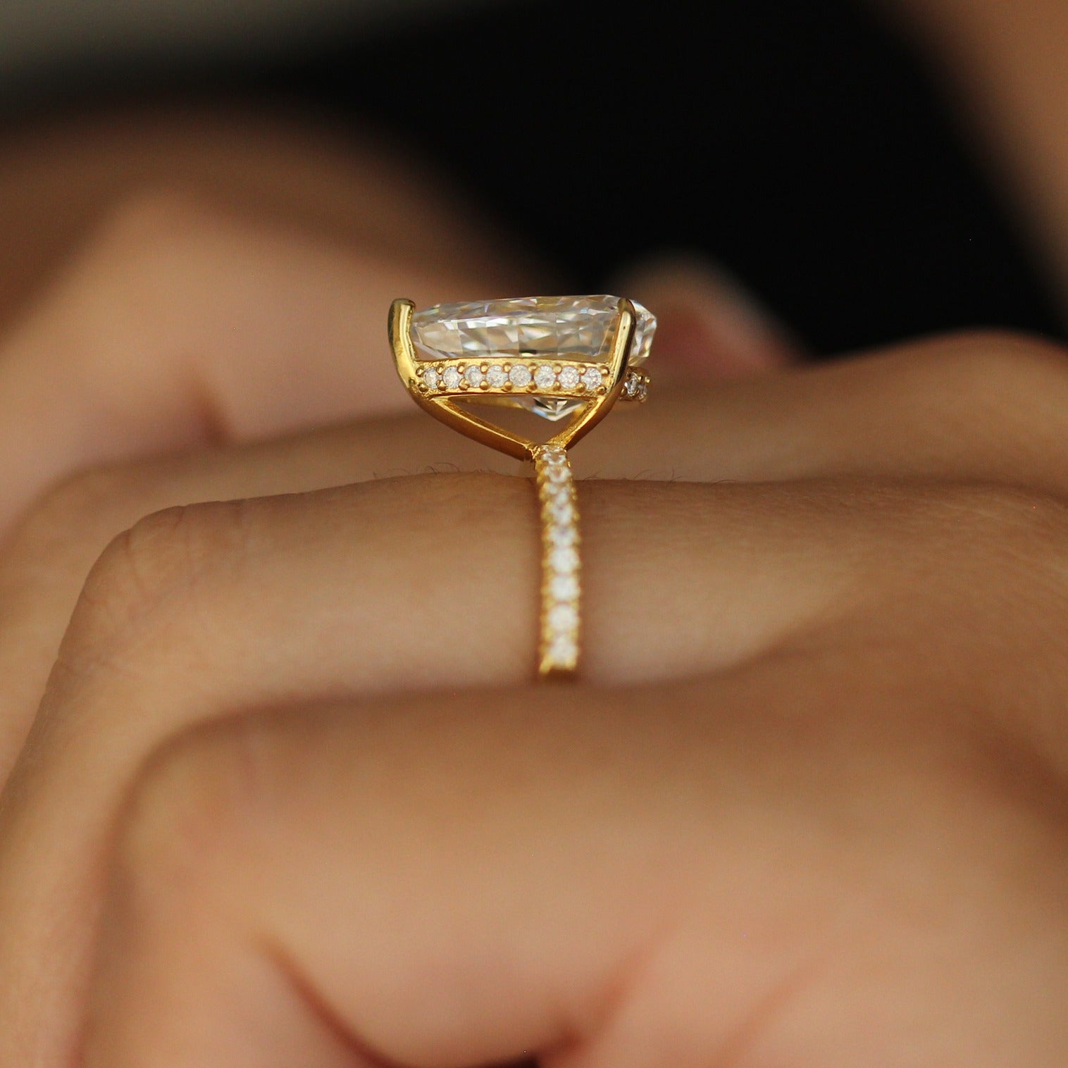 Gold pear ring with side halo on hand