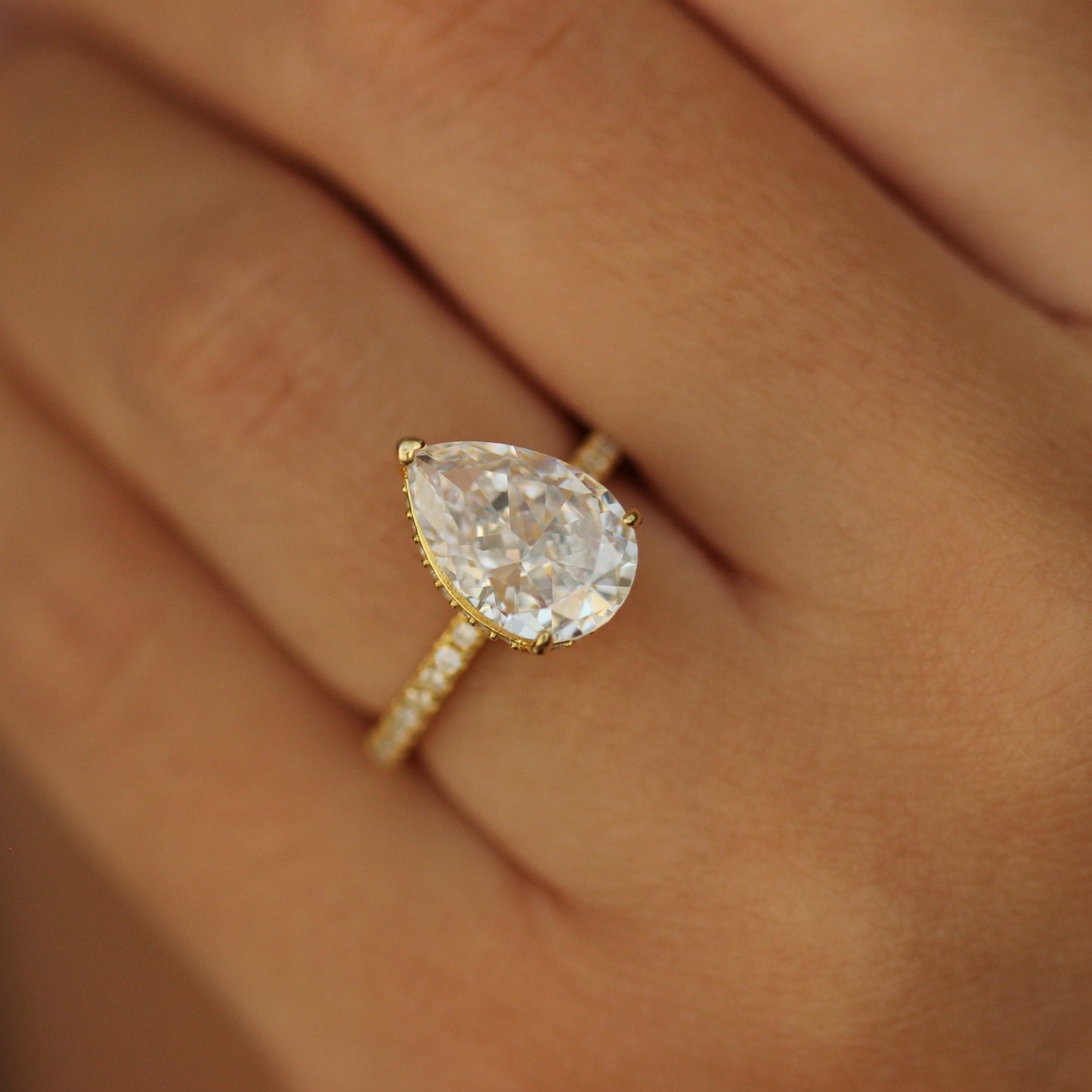 Gold pear ring with side halo on hand