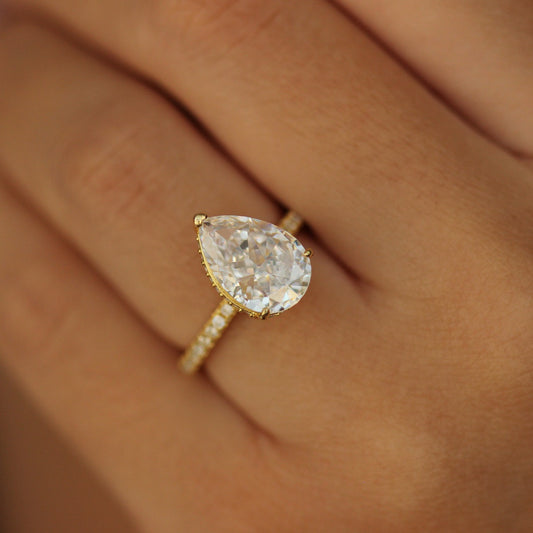 Gold pear ring with side halo on hand