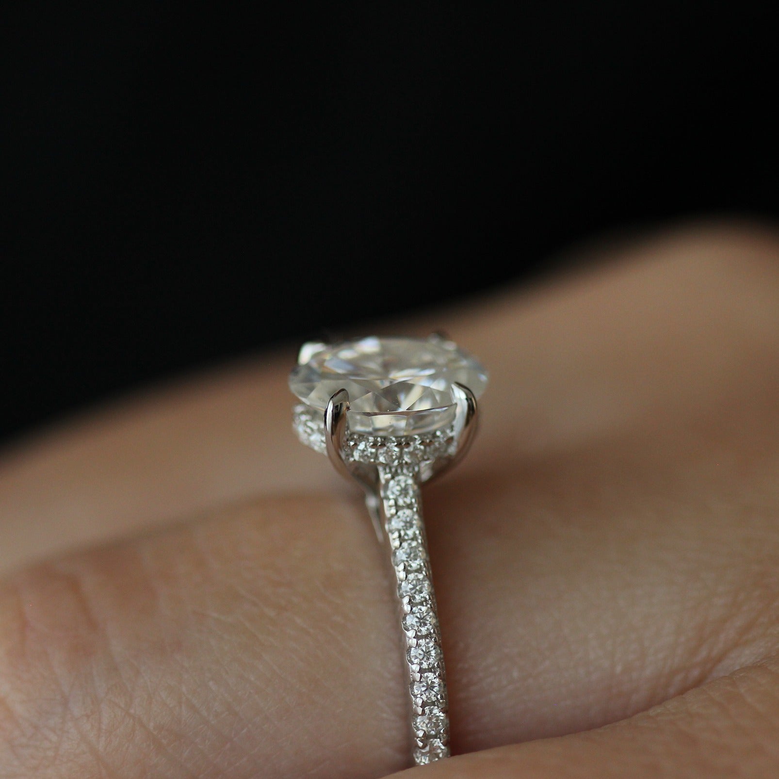 Side view of 2ct oval moissanite ring with pave band on hand