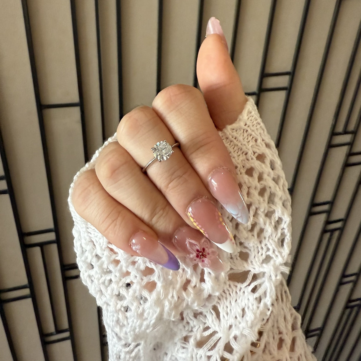 Hand wearing a round cut ring against a neutral background