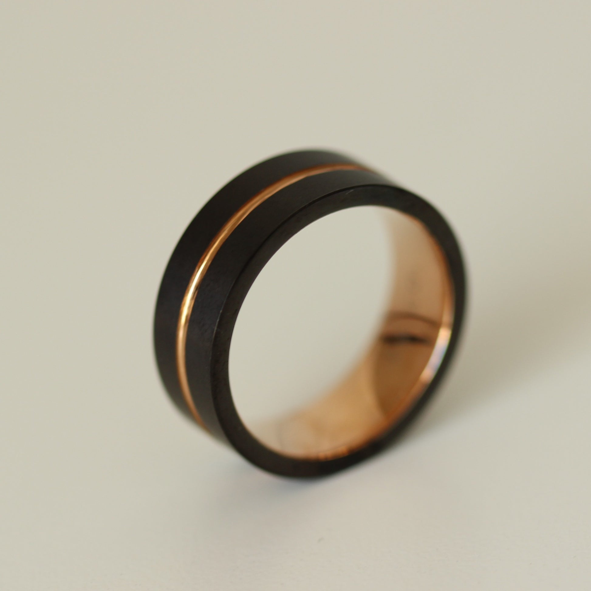 Rose gold black mens ring on white background