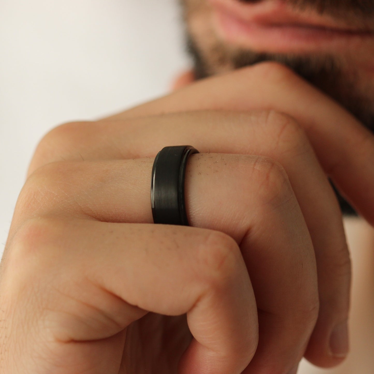 Male model looking sideways wearing Black Men’s Ring 8mm with stepped edge