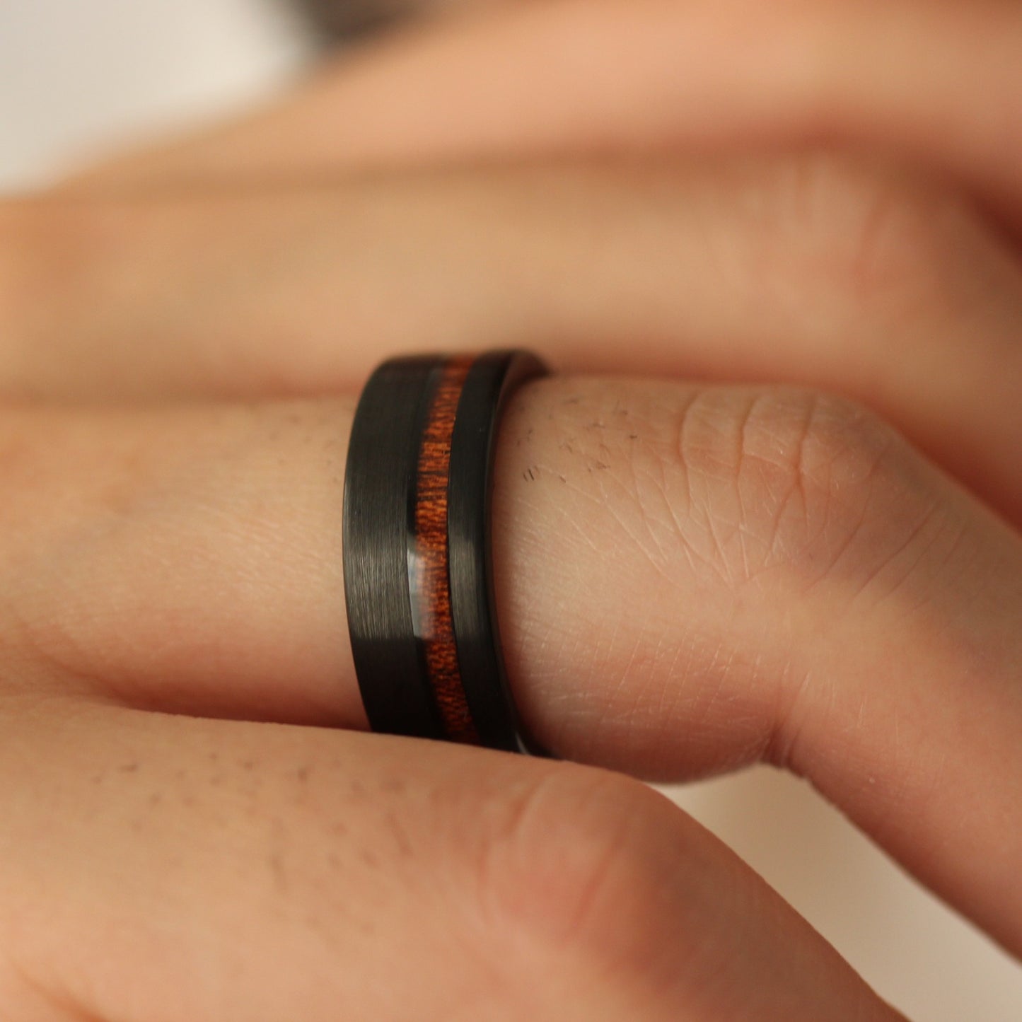 Close up of a hand wearing a black ring with a red inlay