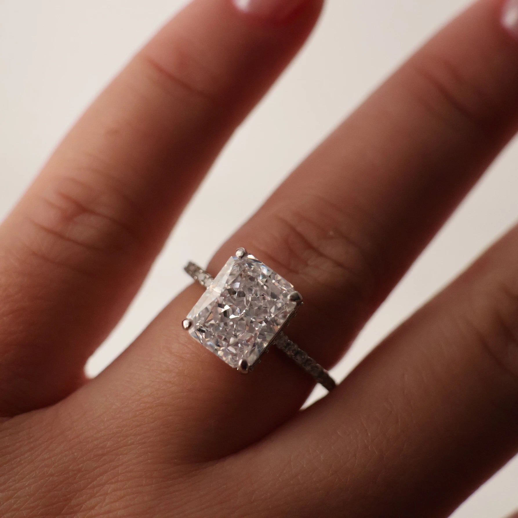 Close up of a 3.5 ct radiant cut cubic zirconia ring with a pavé band in silver
