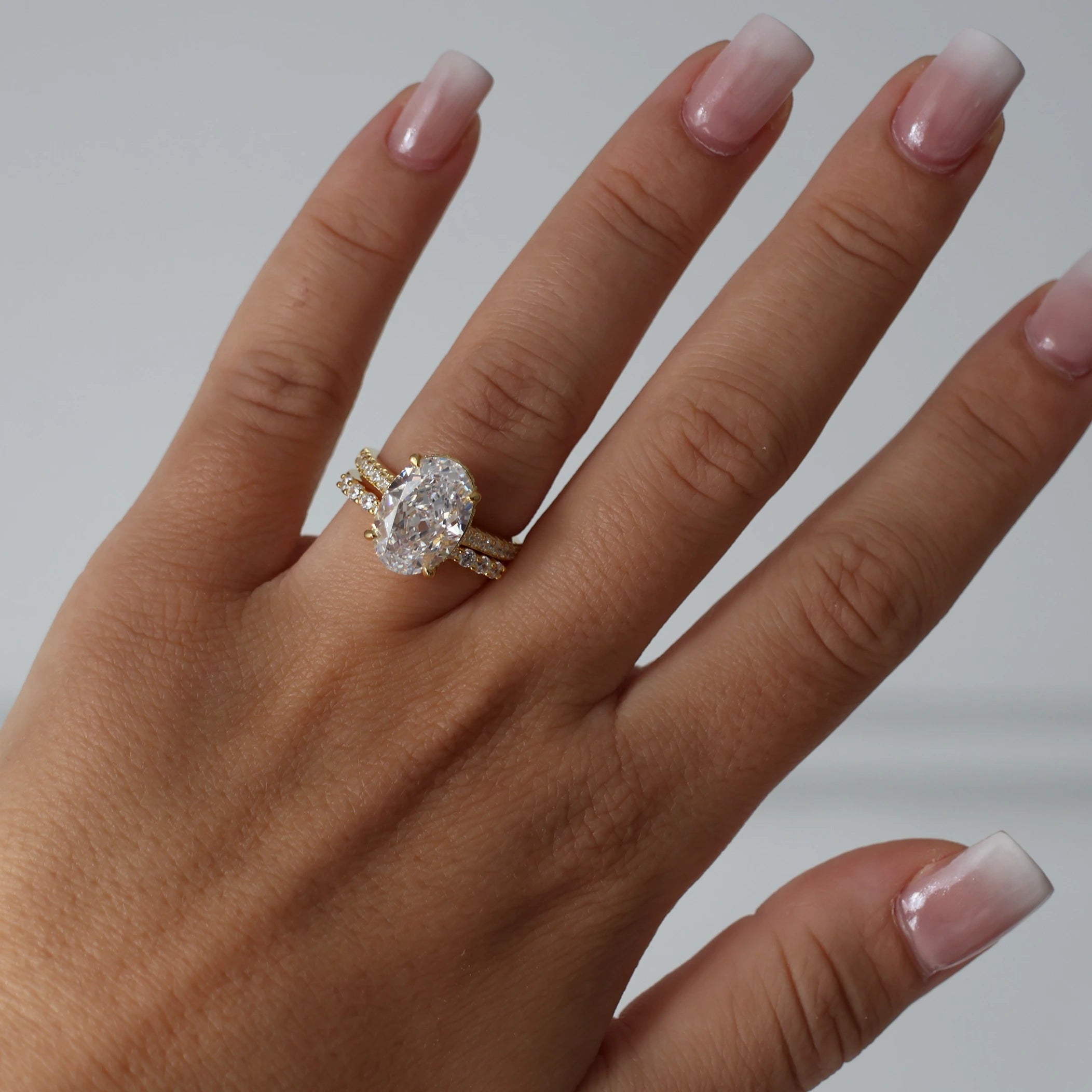 Gold pavé band ring with 4 carat oval cubic zirconia center stone and hidden halo design