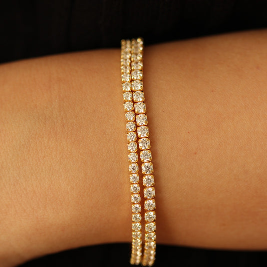 3mm Gold tennis bracelet with clear stones on a wrist against a dark background