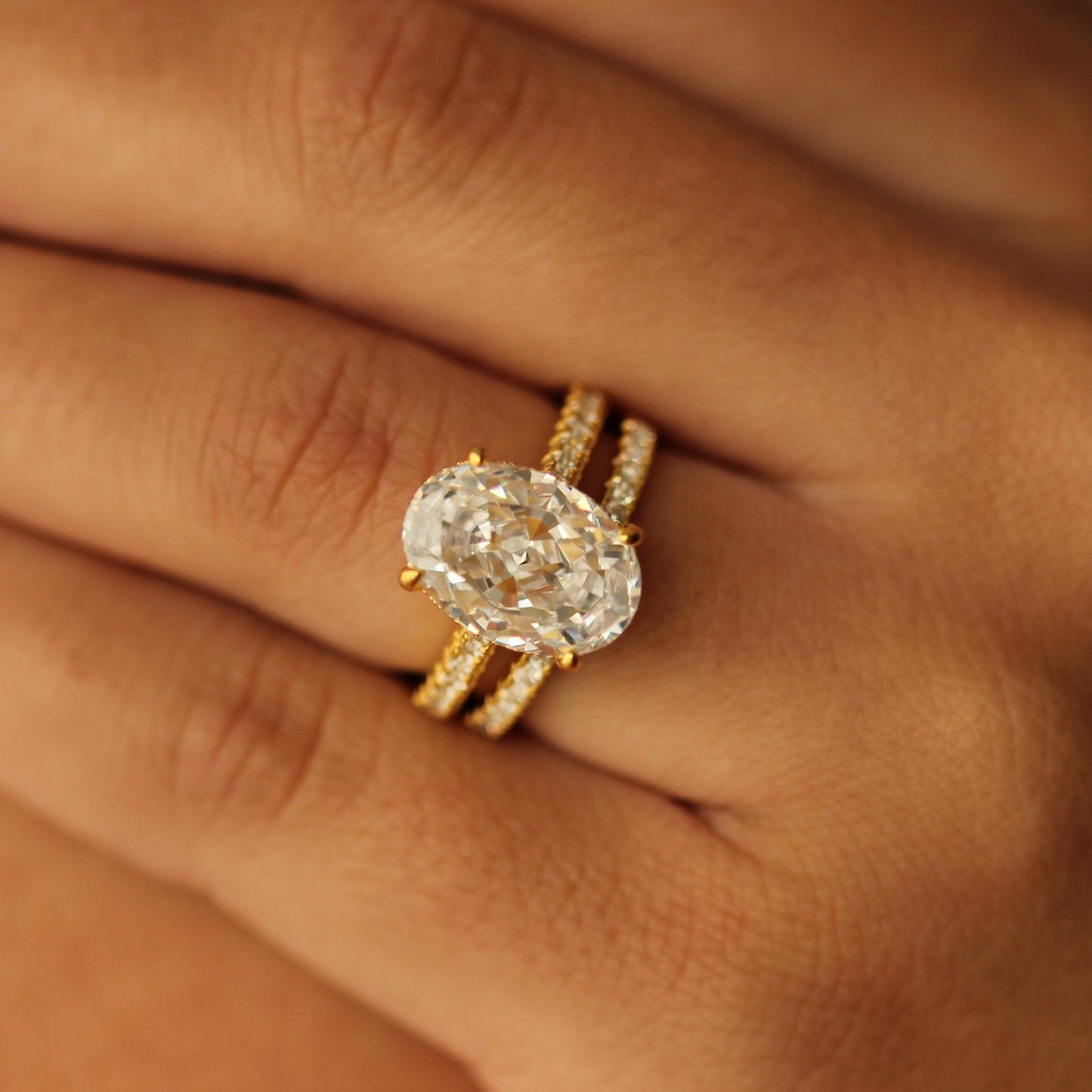4 carat gold oval ring on pave band on hand with half pave band