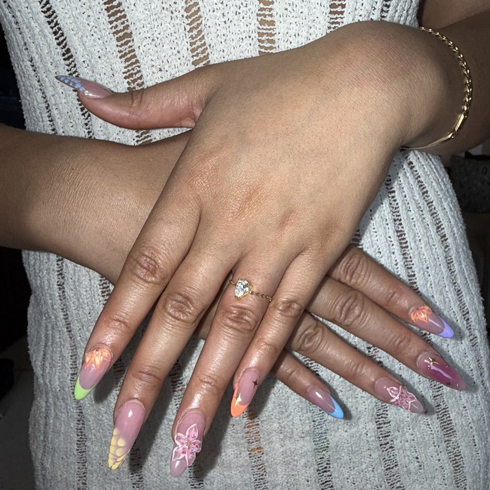 Close-up of hands with colorful nail polish and a pear adjustable ring, wearing a textured garment.