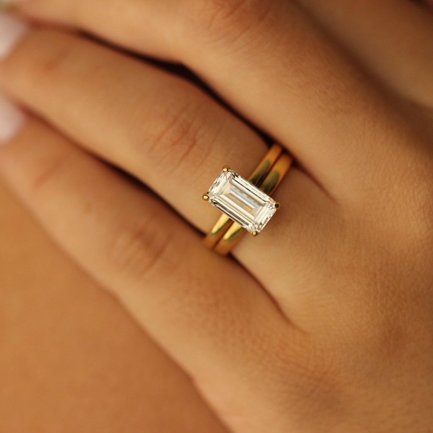 18k plain gold wedding band with emerald cut ring on hand
