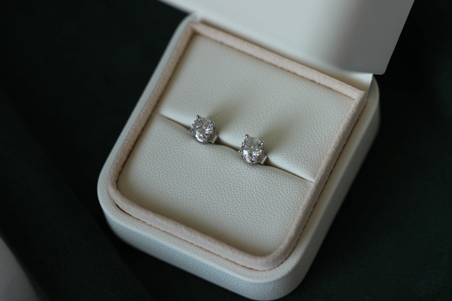 1tcw moissanite stud earrings in a white jewelry box on a dark background