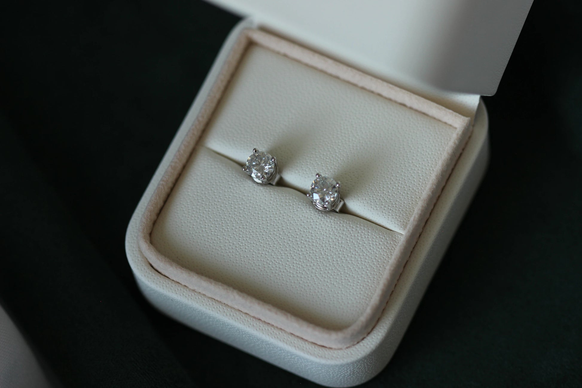 1tcw moissanite stud earrings in a white jewelry box on a dark background