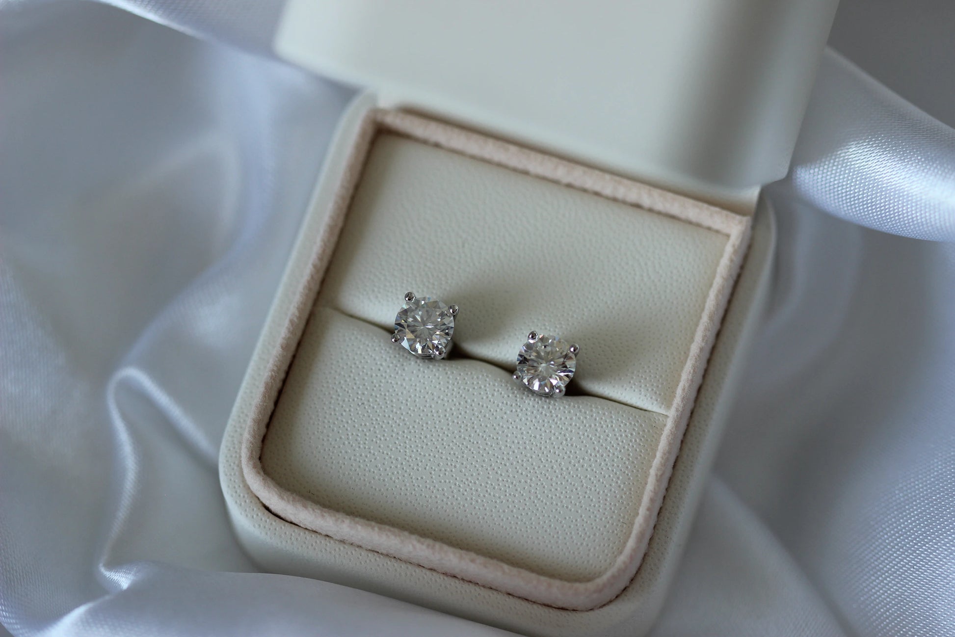 2tcw Moissanite earrings in a beige jewelry box on a white fabric background