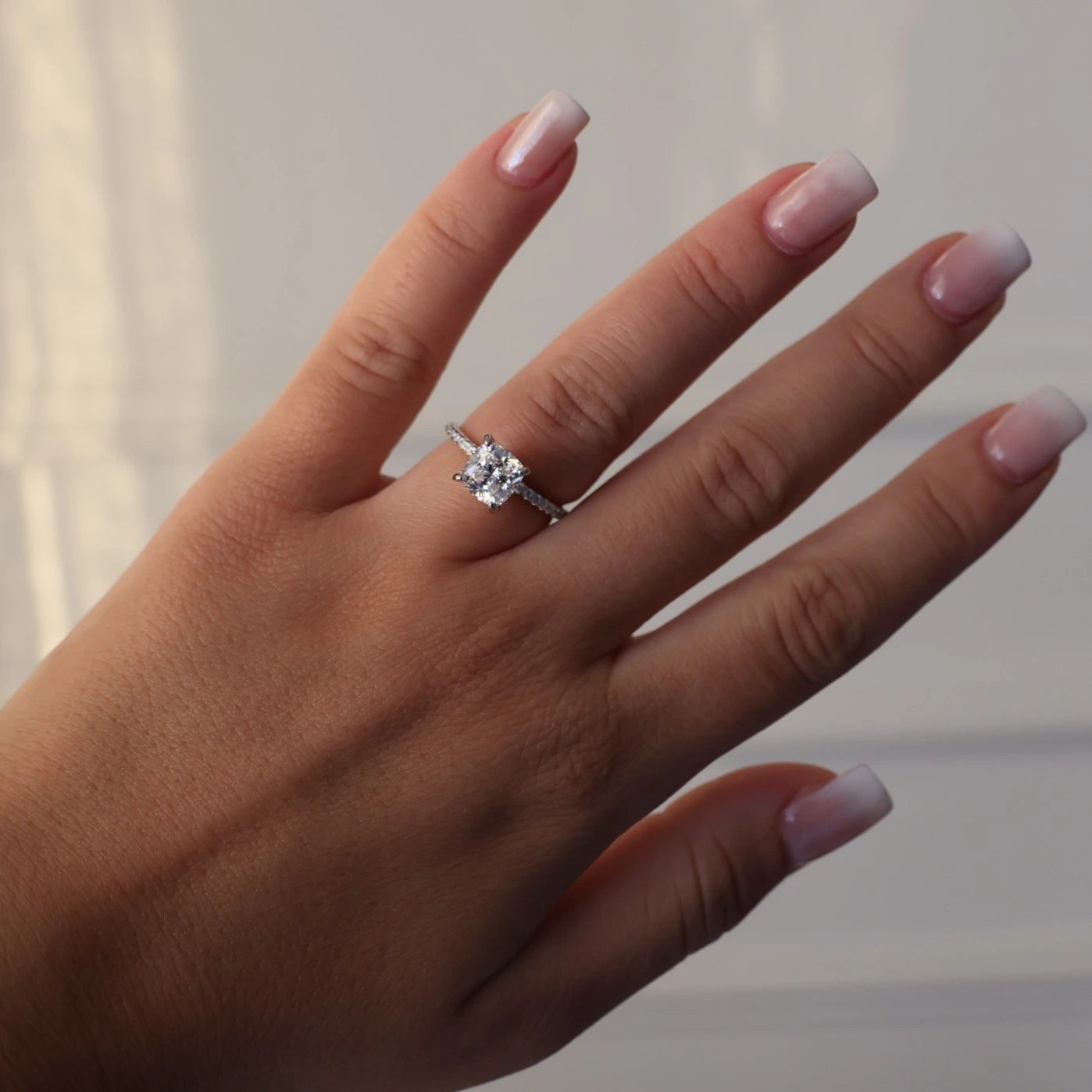 Silver ring featuring a 2 carat cushion cut cubic zirconia and pavé set band