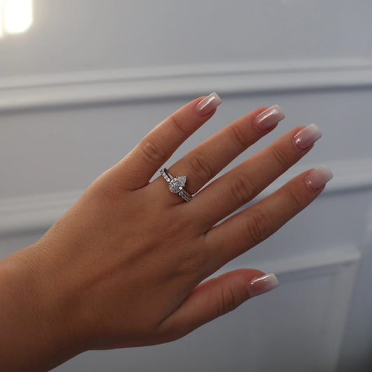 pear shaped silver solitaire ring stacked with open band