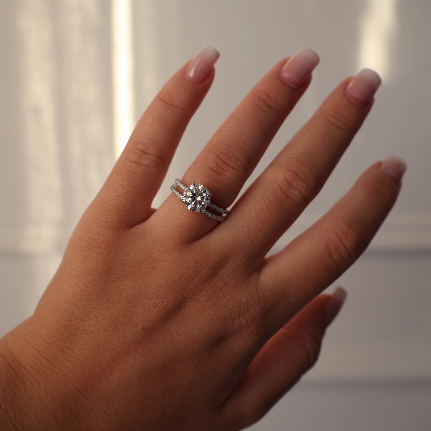 Silver engagement ring with a 2 carat round moissanite and pave band