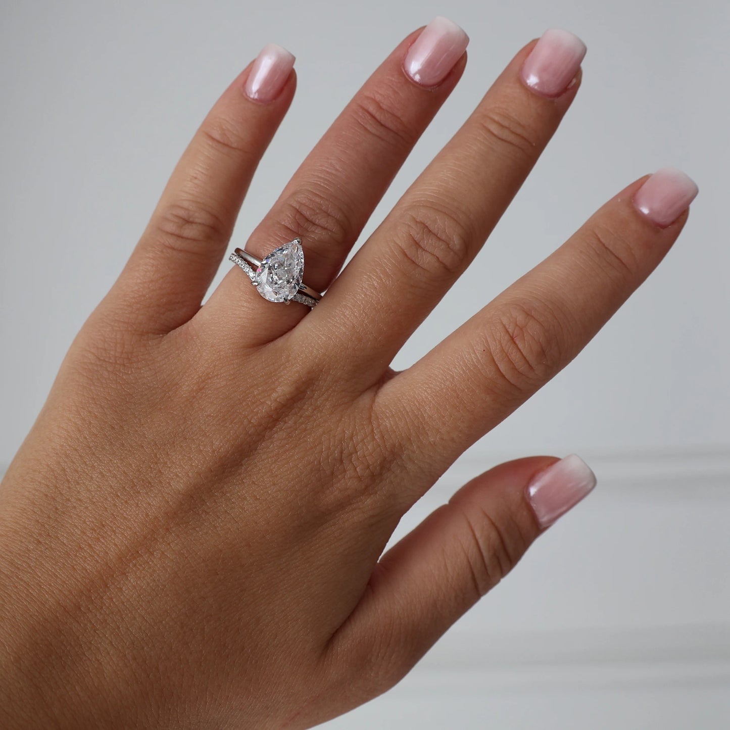 Silver wishbone ring stacked with a pear cut cubic zirconia engagement ring