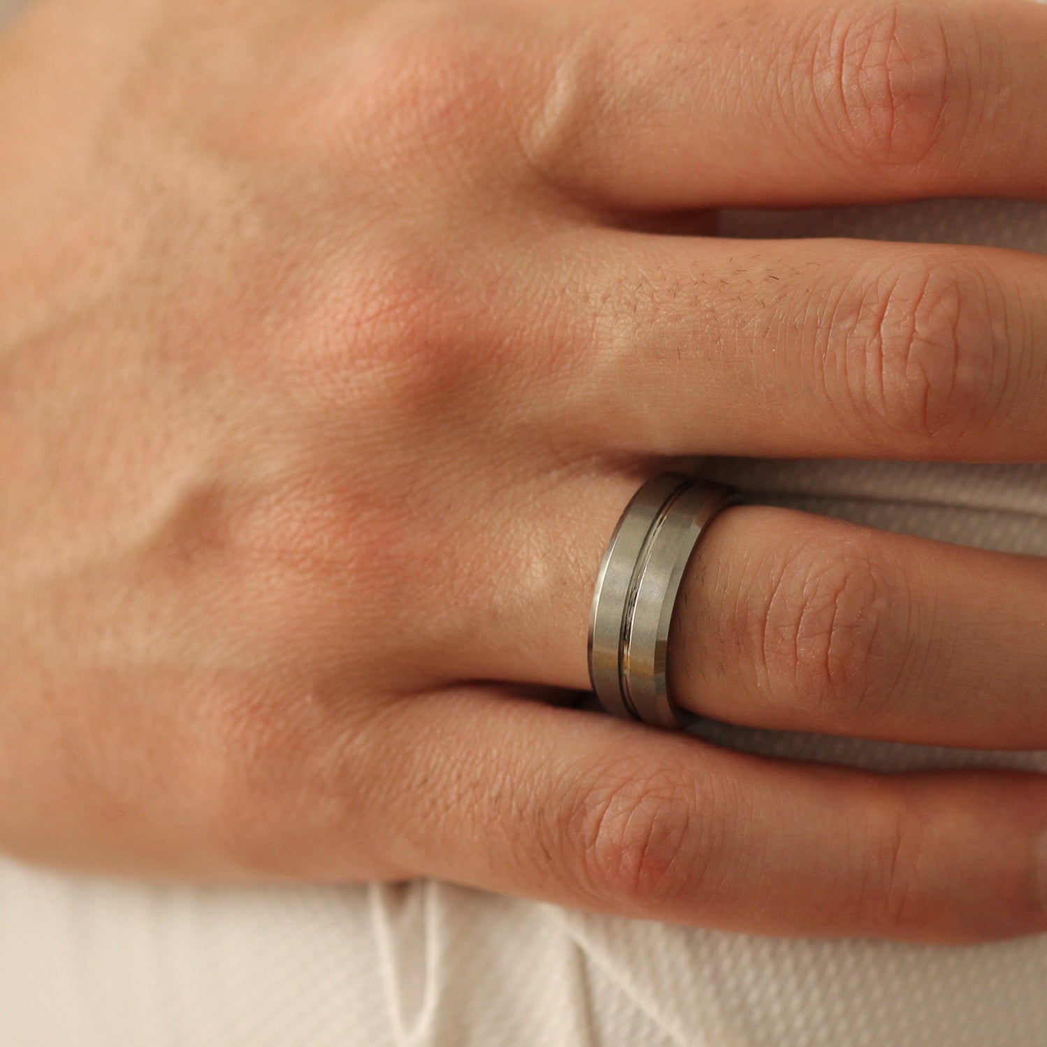 Male model with hands crossed wearingSilver Men’s Ring 8mm with grooved line design