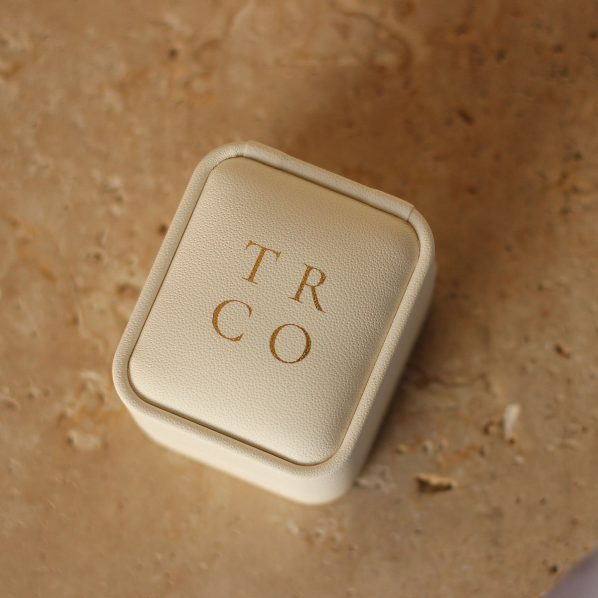 Travel Ring Co ivory wedding ring box in front of stone background