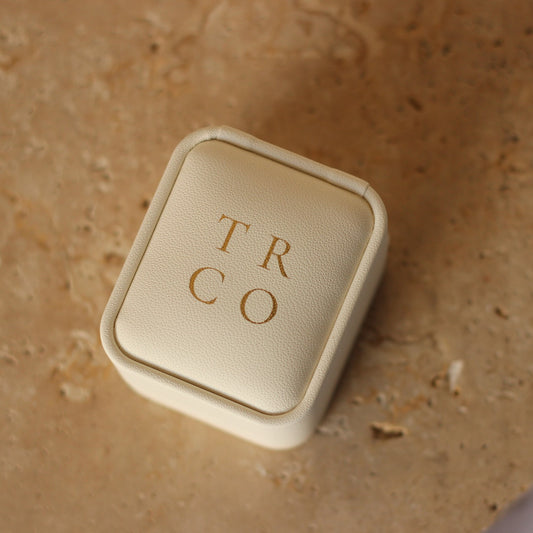 Travel Ring Co ivory wedding ring box in front of stone background