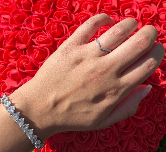 person wearing silver wishbone ring on top of rose pillow
